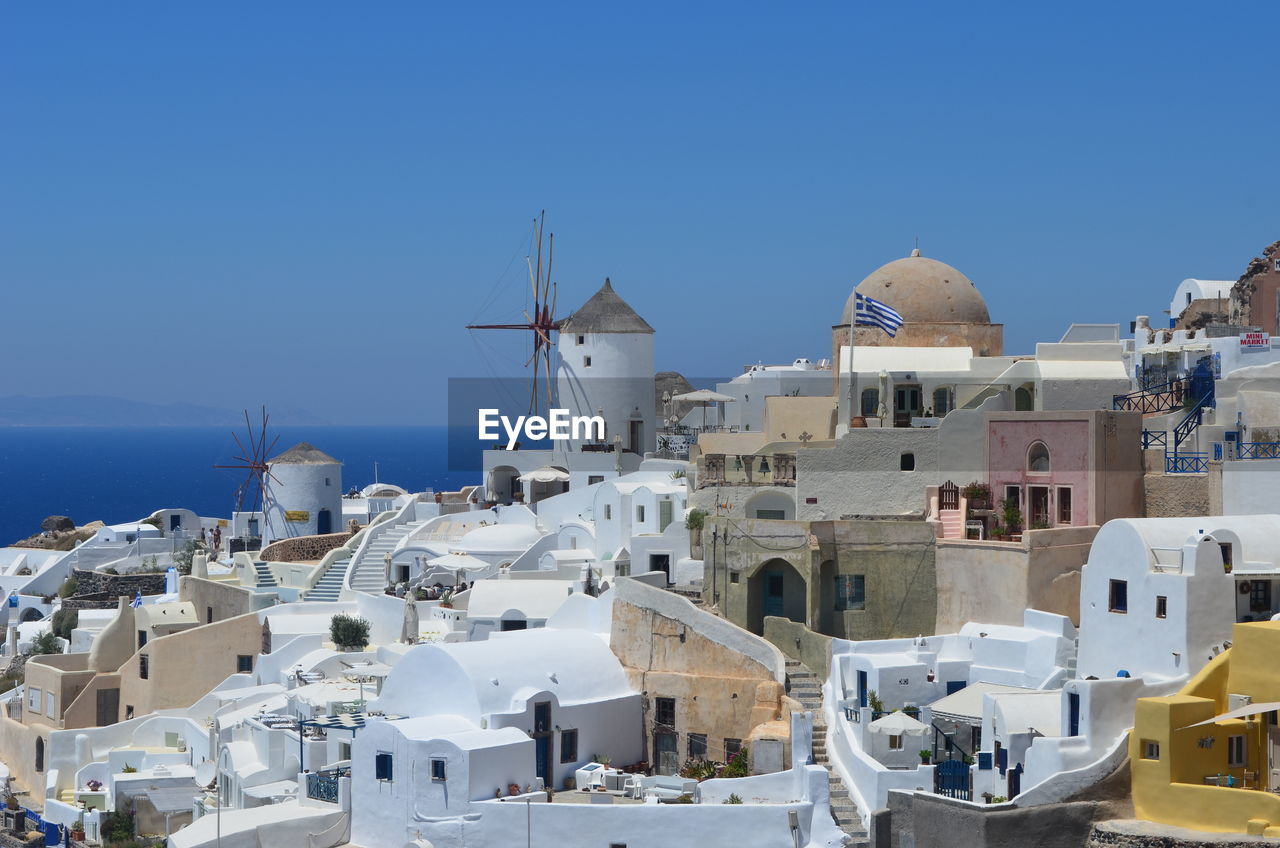 Traditional windmill in town at santorini against clear blue sky