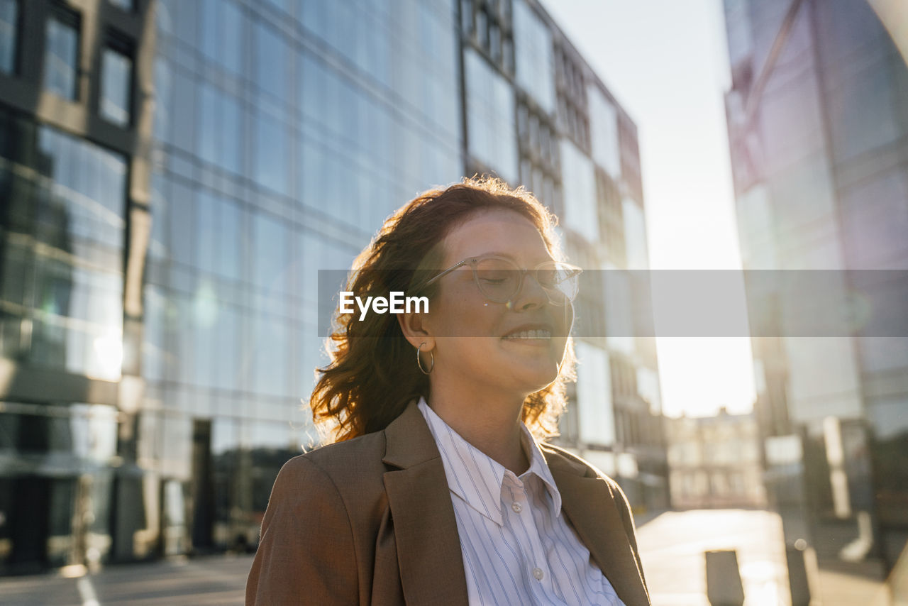 Smiling businesswoman day dreaming with eyes closed