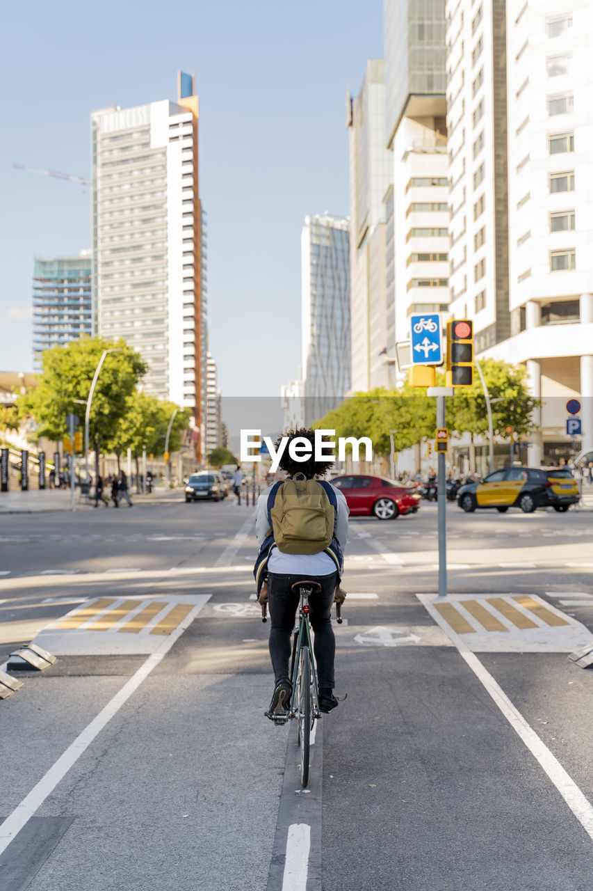 Rear view of casual businessman on bicycle in the city, barcelona, spain