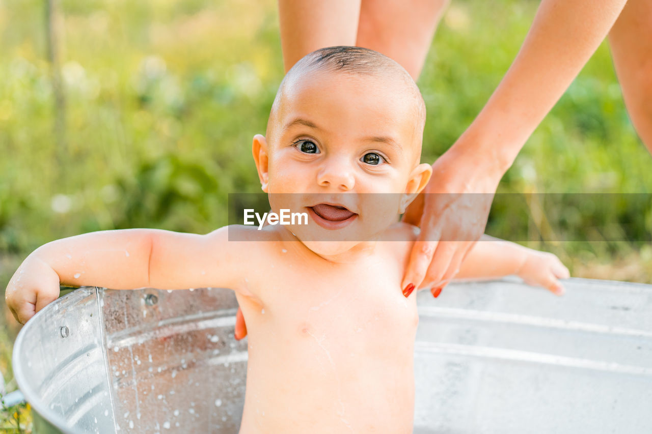 Portrait of shirtless boy sitting in bathtub outdoors