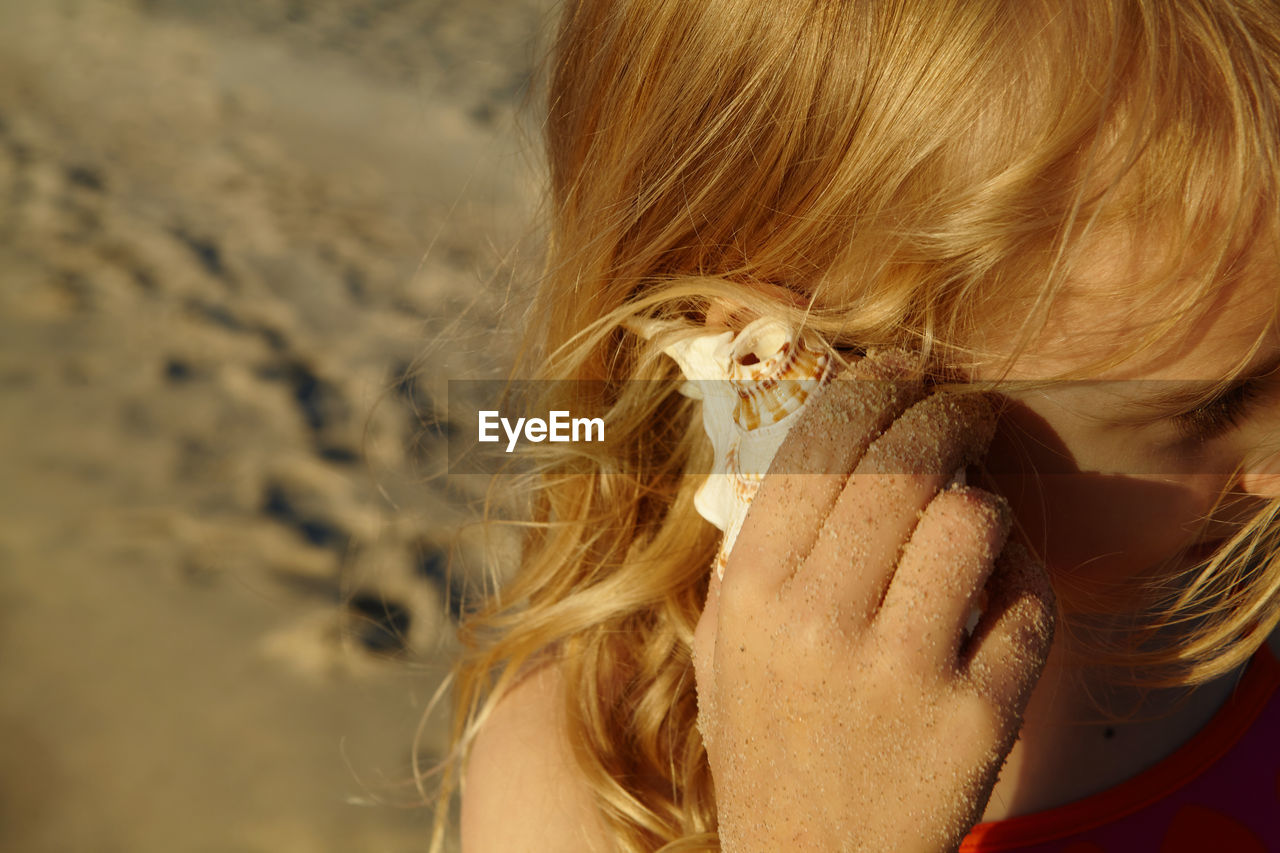 Close-up of girl listening through seashell