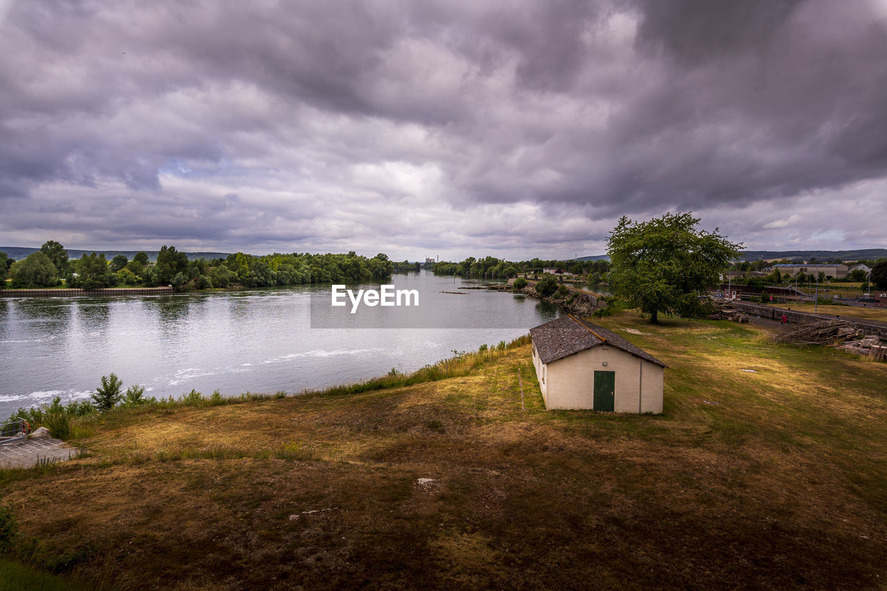 House by lake and buildings against sky. solitude concept