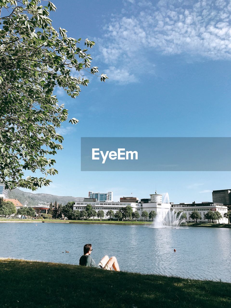 Man looking at lake in city against sky