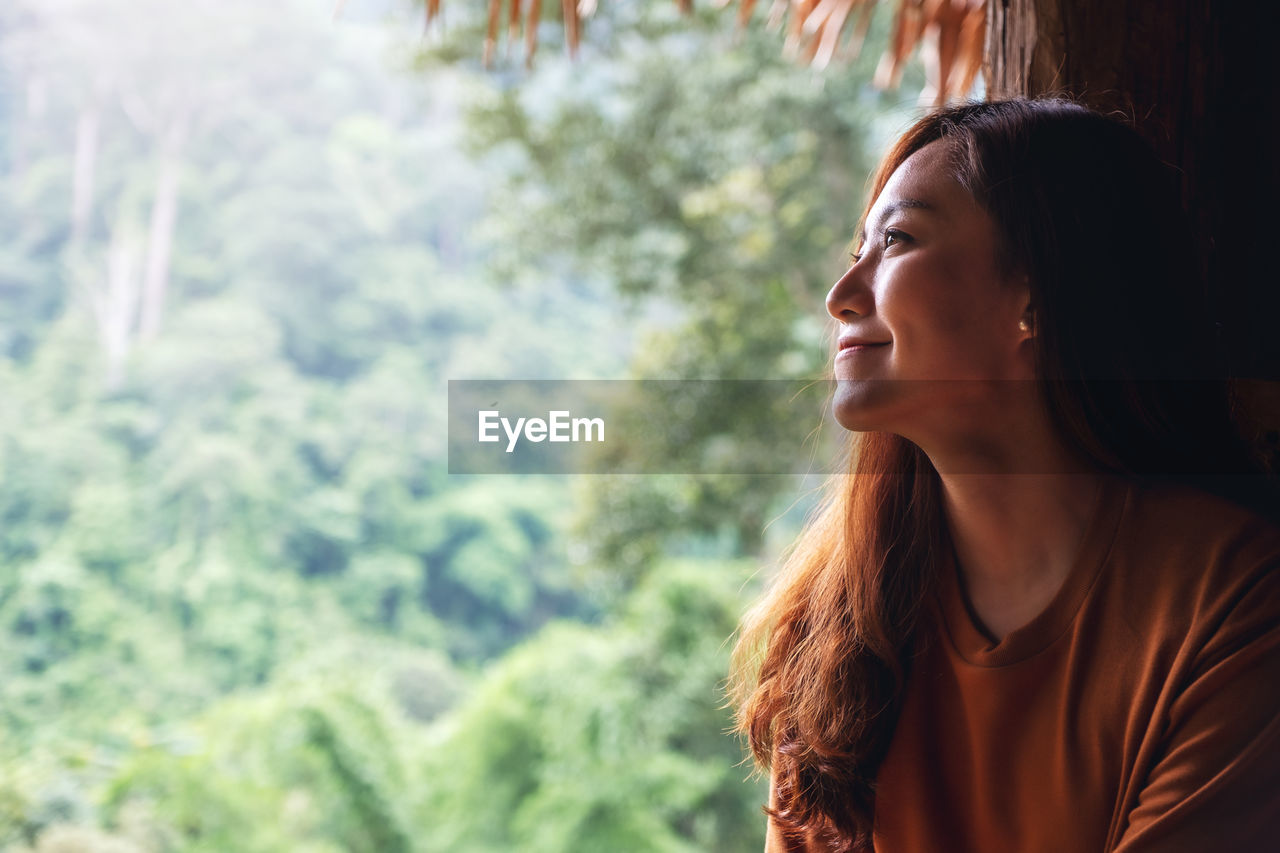 Portrait image of a beautiful female traveler looking at a beautiful green mountain view