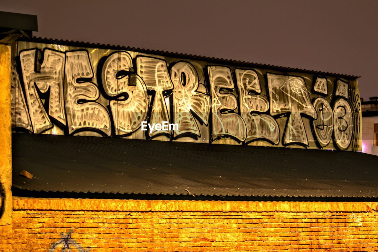 architecture, art, built structure, no people, building exterior, wall, text, graffiti, wall - building feature, creativity, sky, yellow, illuminated, outdoors, night, communication, nature, travel destinations, history, low angle view