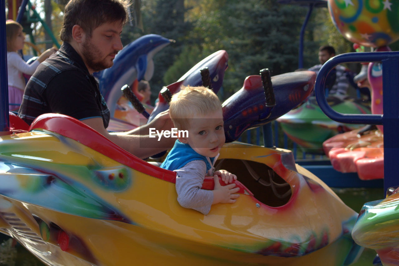 SIBLINGS PLAYING ON AMUSEMENT PARK RIDE