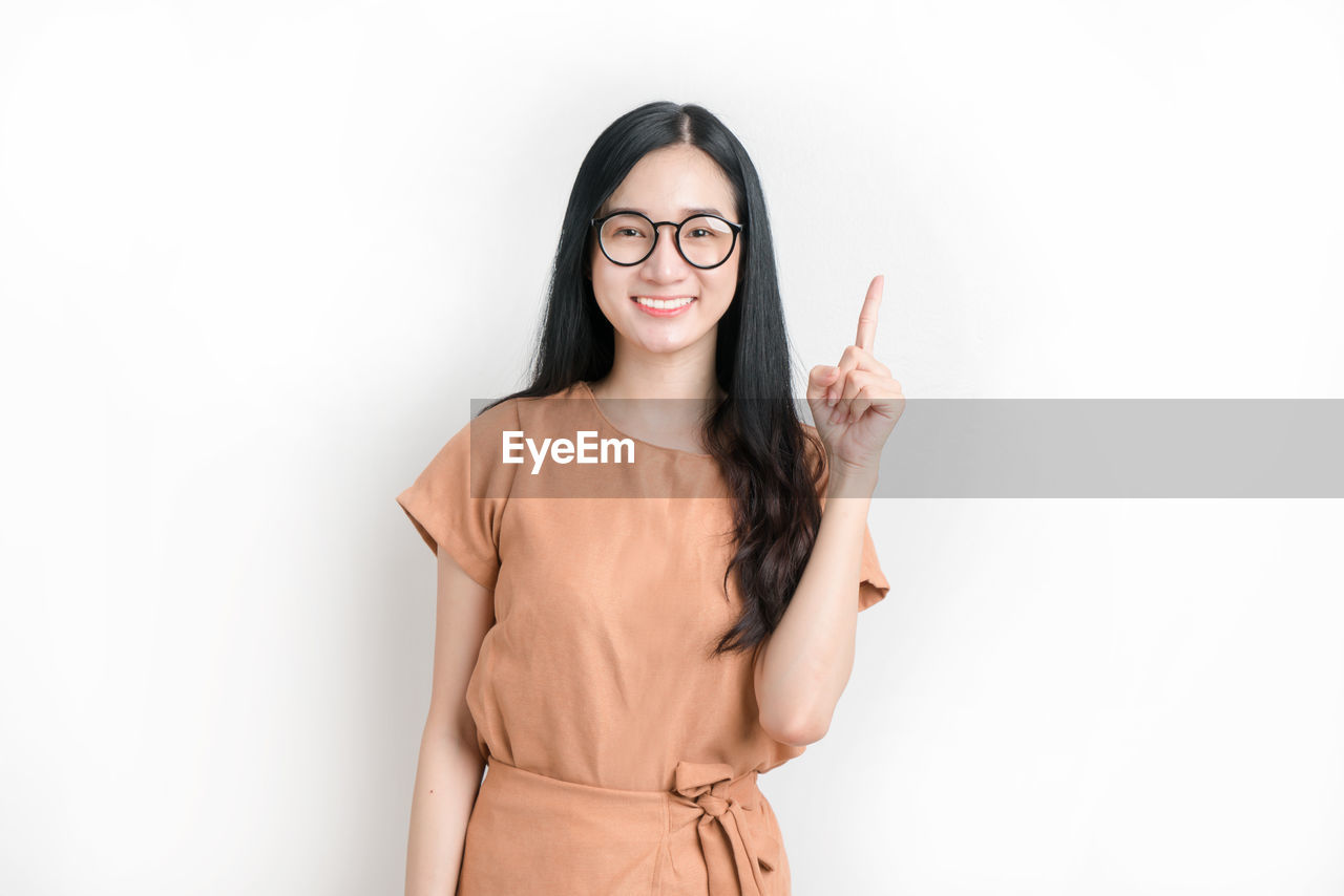 PORTRAIT OF YOUNG WOMAN AGAINST WHITE BACKGROUND