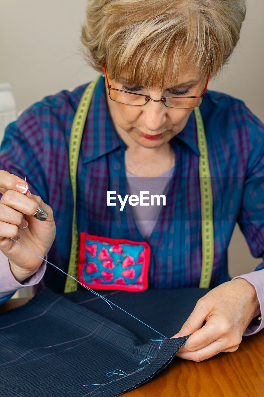 MIDSECTION OF WOMAN HOLDING EYEGLASSES ON TABLE