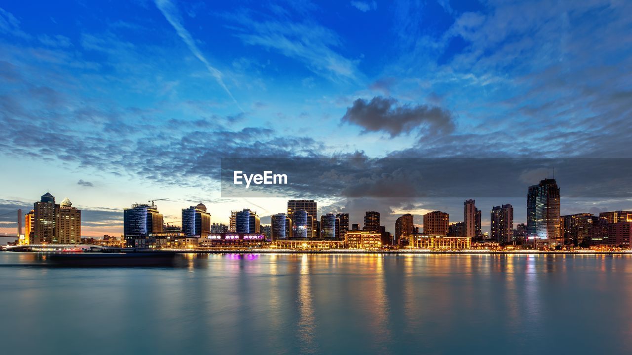 Illuminated buildings in city against sky