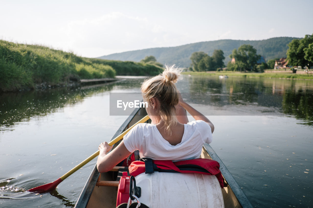 Rear view of woman rowing boat in lake
