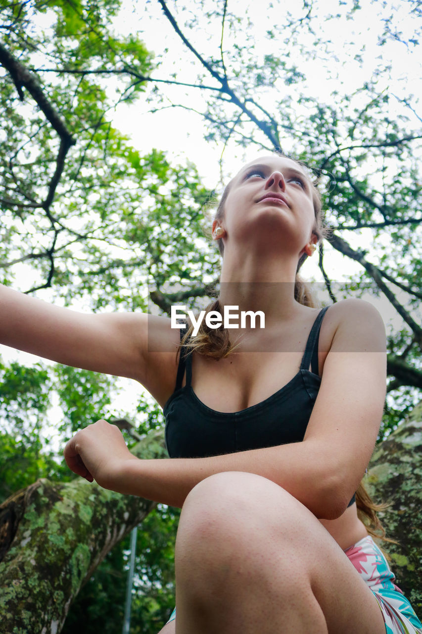 Low angle view of young woman on tree