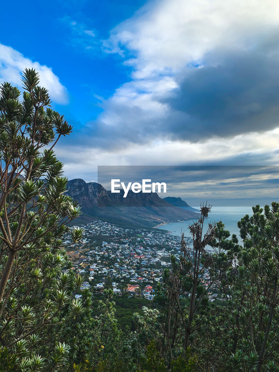 Scenic view of town by mountain against sky