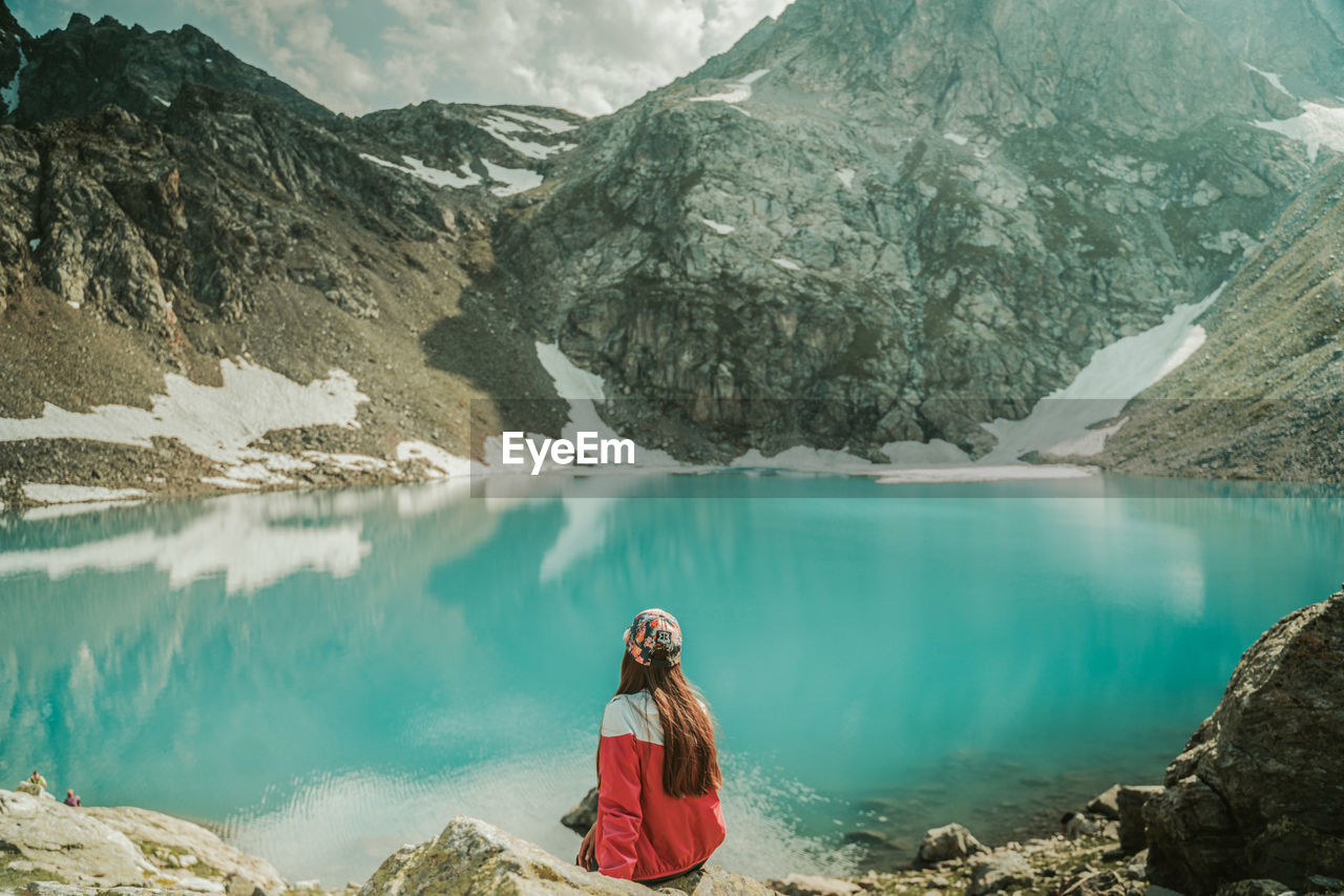 WOMAN IN LAKE AGAINST MOUNTAINS