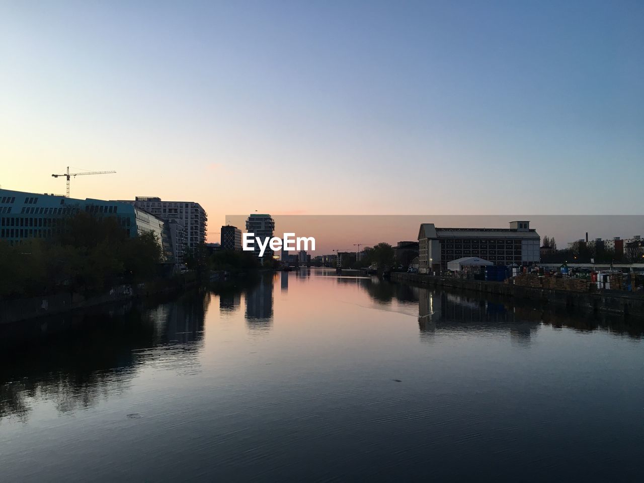 BUILDINGS AND RIVER AGAINST SKY DURING SUNSET