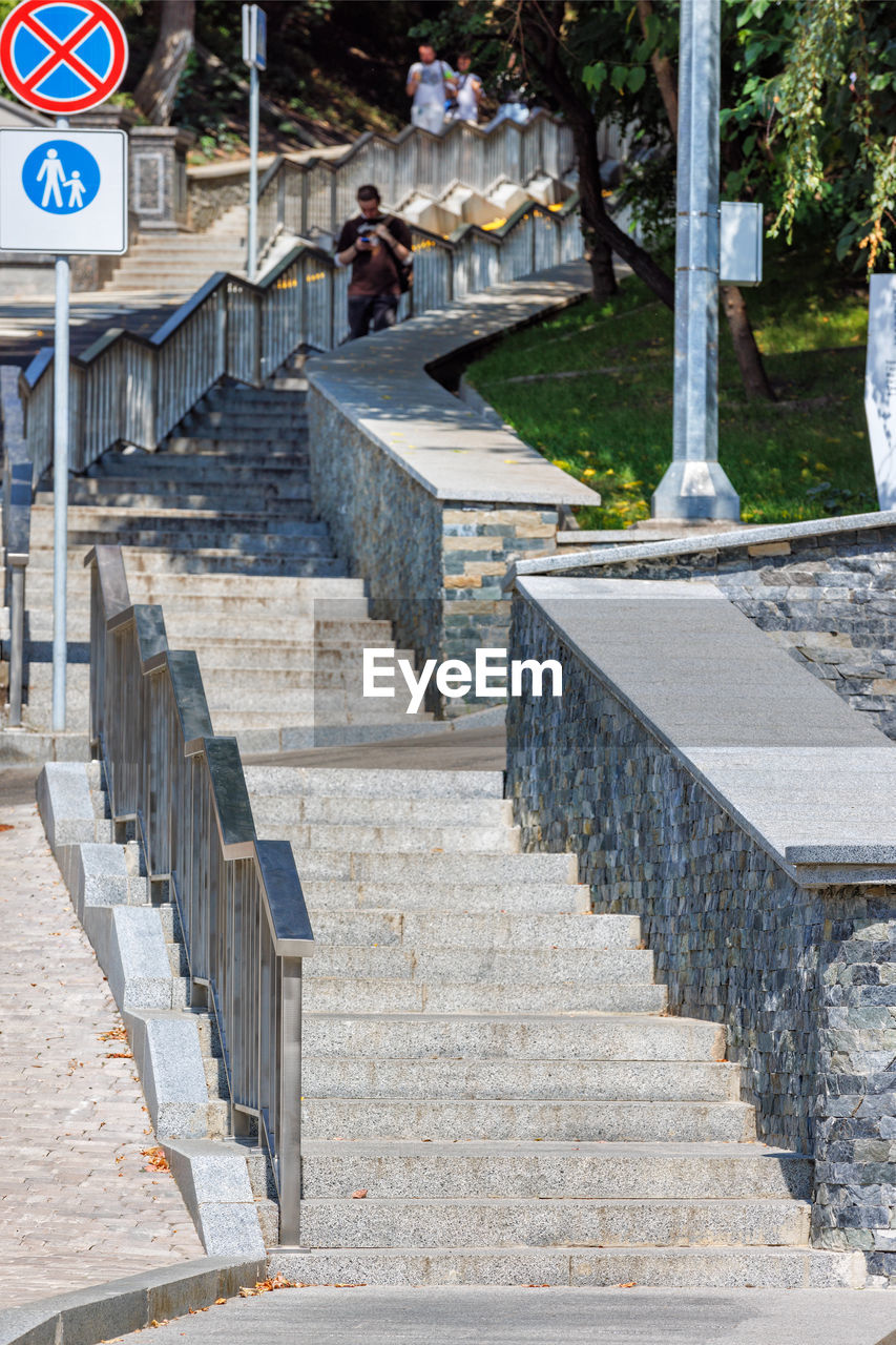 staircase, architecture, walkway, steps and staircases, sign, communication, wall, day, built structure, nature, road sign, outdoors, no people, stairs, city, tree, text, railing, road, road surface