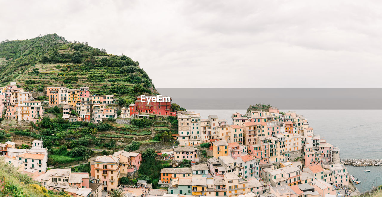 HIGH ANGLE VIEW OF TOWNSCAPE AND SEA AGAINST SKY