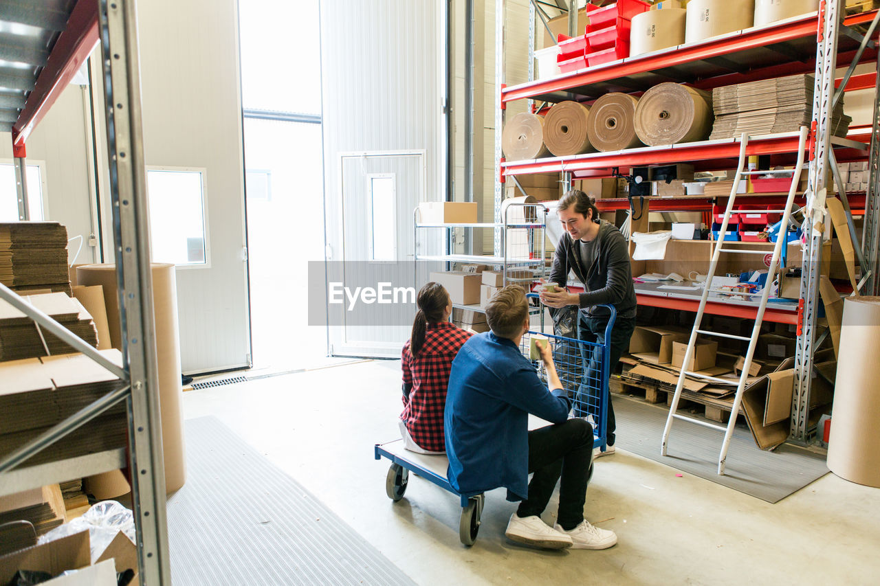 Male and female coworkers discussing during coffee break in warehouse