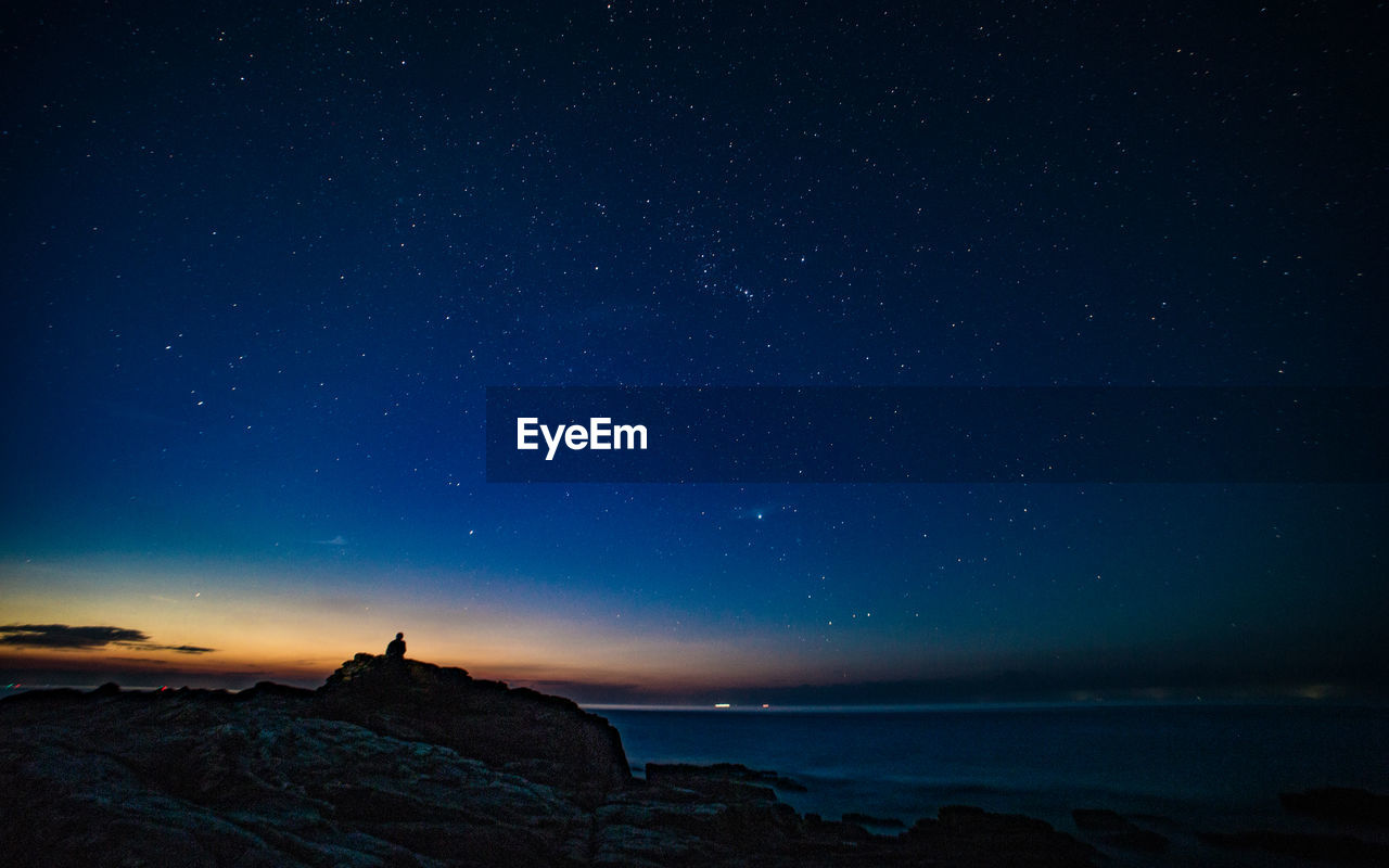 Scenic view of sea against star field at night