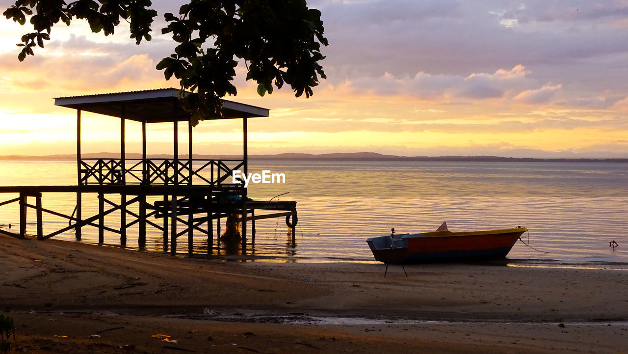 Golden sunrise with silhouette of wooden jetty,fishing boat and tropical tree at labuan ft,malaysia.