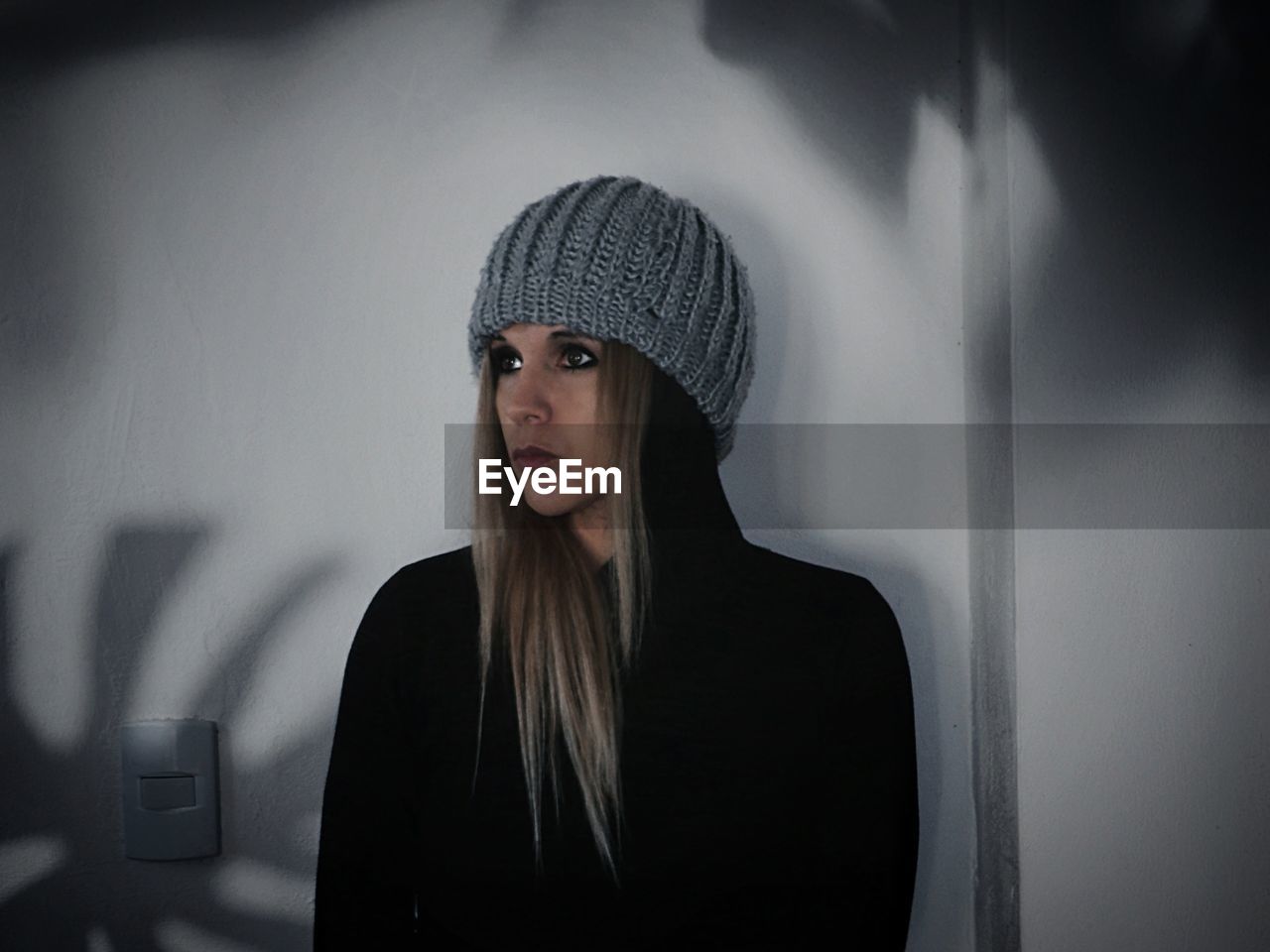 Portrait of young woman standing against wall