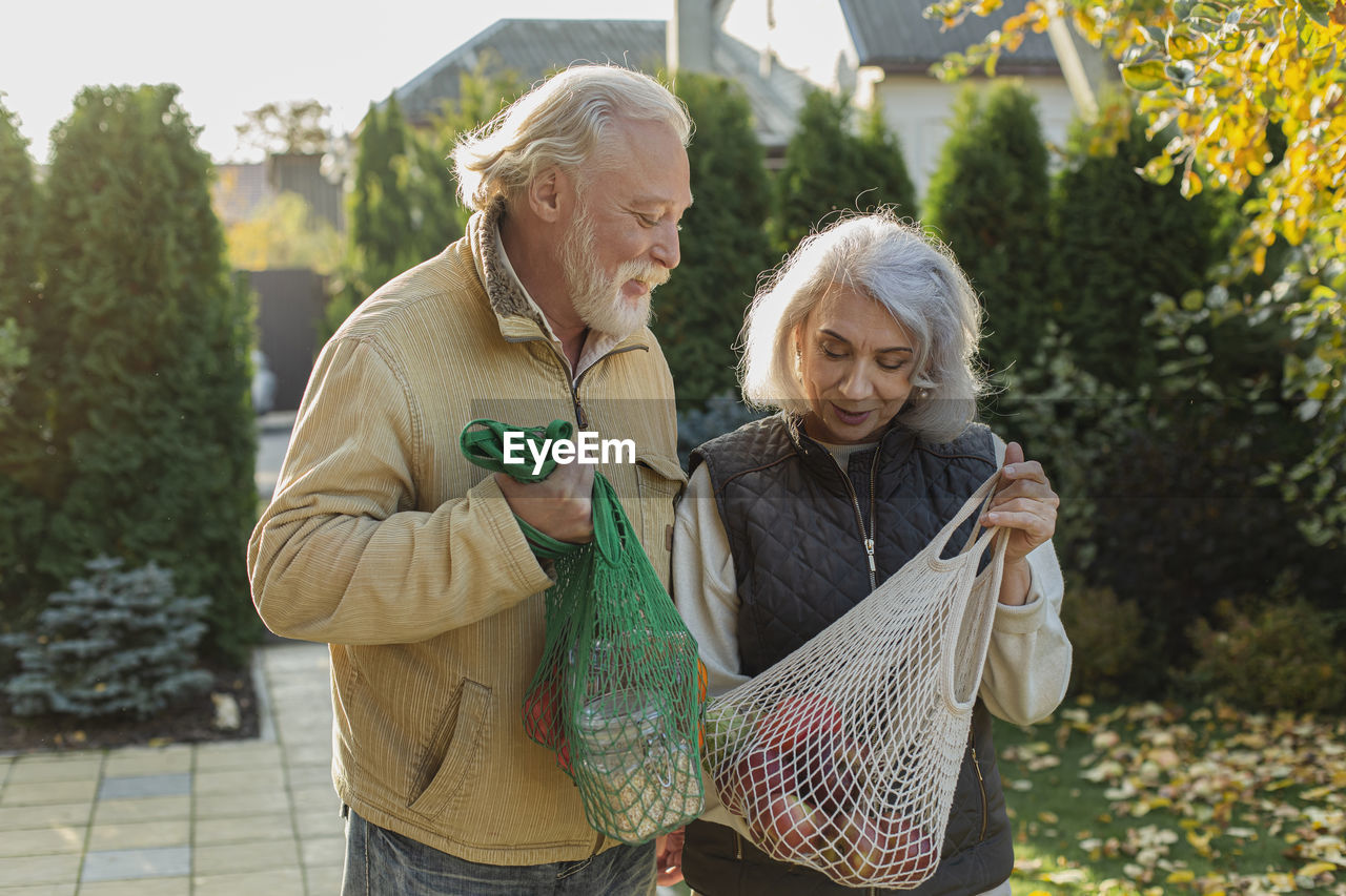 Senior couple carrying groceries in eco-friendly reusable mesh bags
