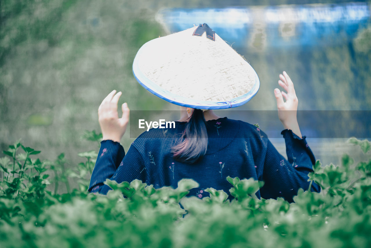 plant, one person, blue, nature, green, hat, adult, flower, clothing, grass, women, sun hat, day, selective focus, land, outdoors, field, lifestyles, rural scene, landscape, person, growth, leisure activity, spring, environment, agriculture, casual clothing, fashion accessory, rear view, summer, relaxation