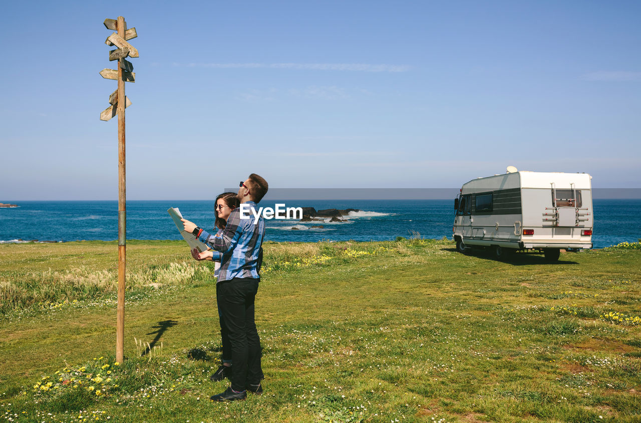 Couple reading sign while holding map on field