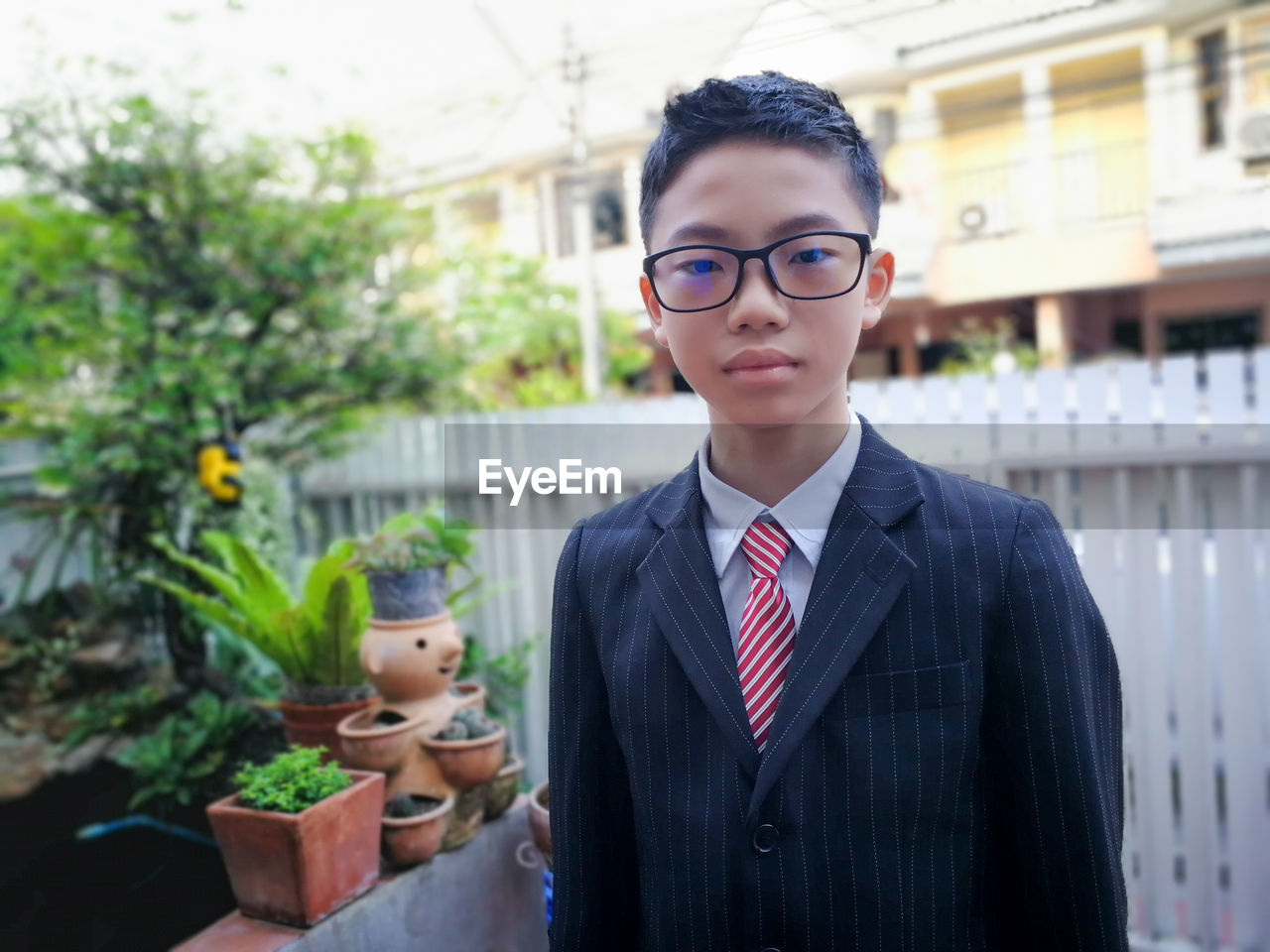 Portrait of boy wearing eyeglasses while standing against house