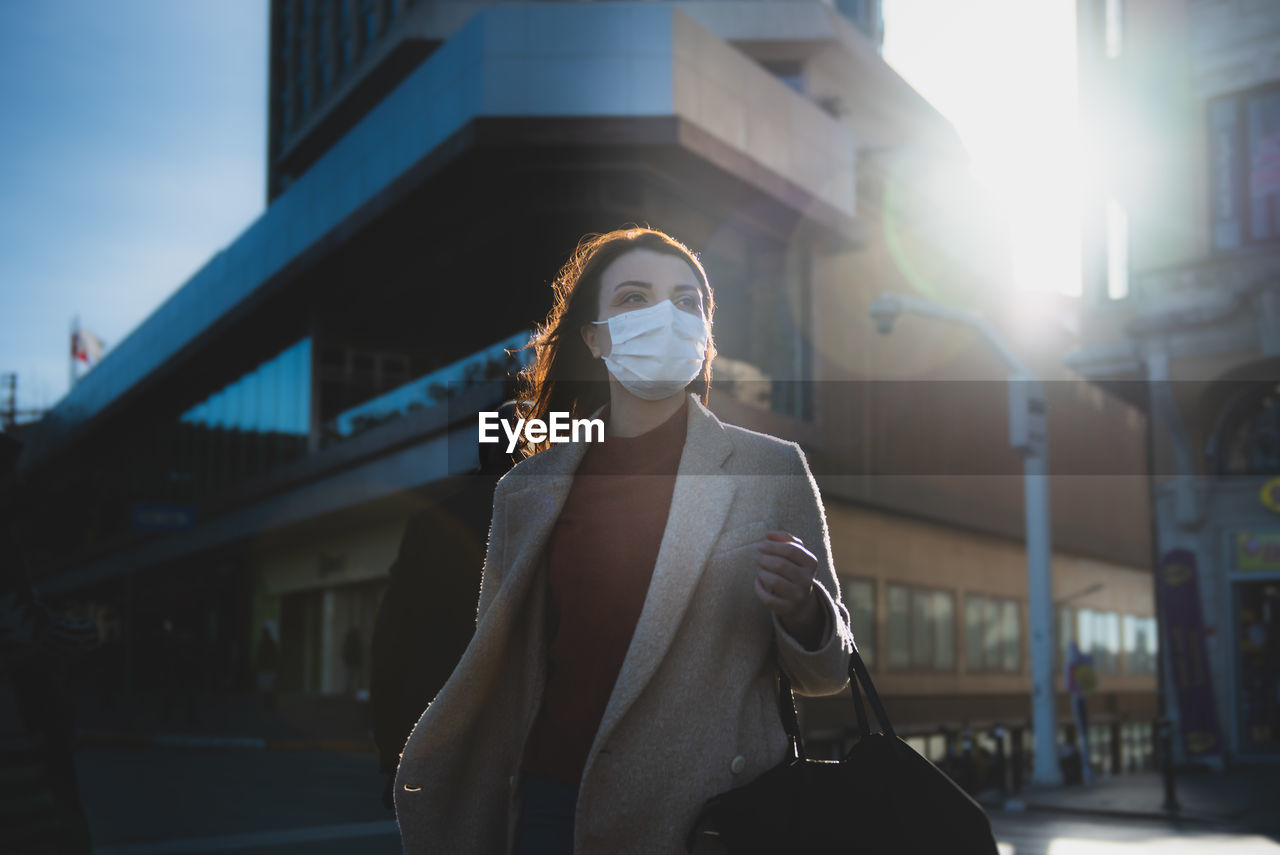 Woman wearing mask on road against buildings