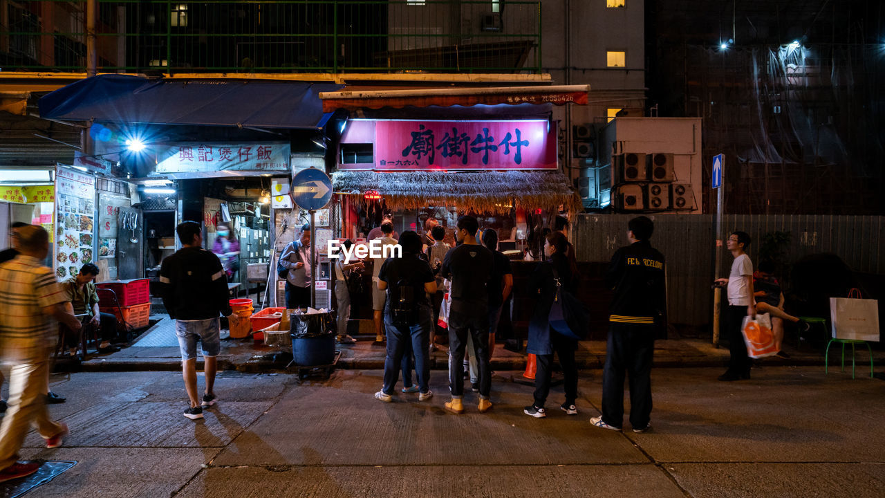 PEOPLE ON ILLUMINATED STREET AT NIGHT