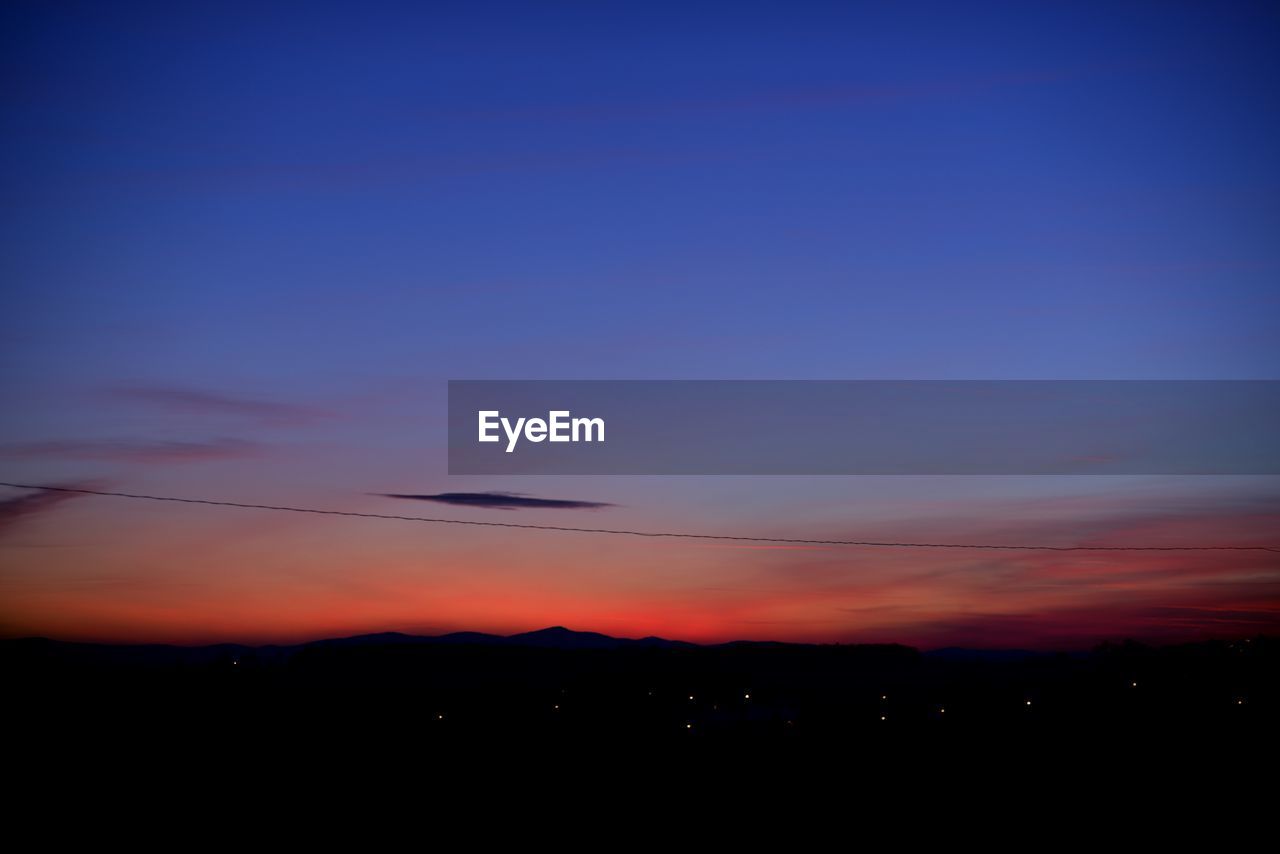 SCENIC VIEW OF SKY OVER SILHOUETTE LANDSCAPE AGAINST SUNSET
