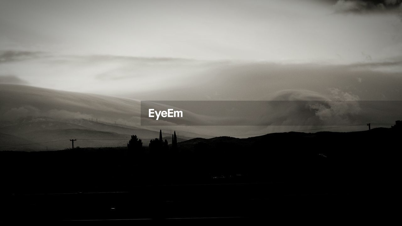 Scenic view of silhouette field against cloudy sky