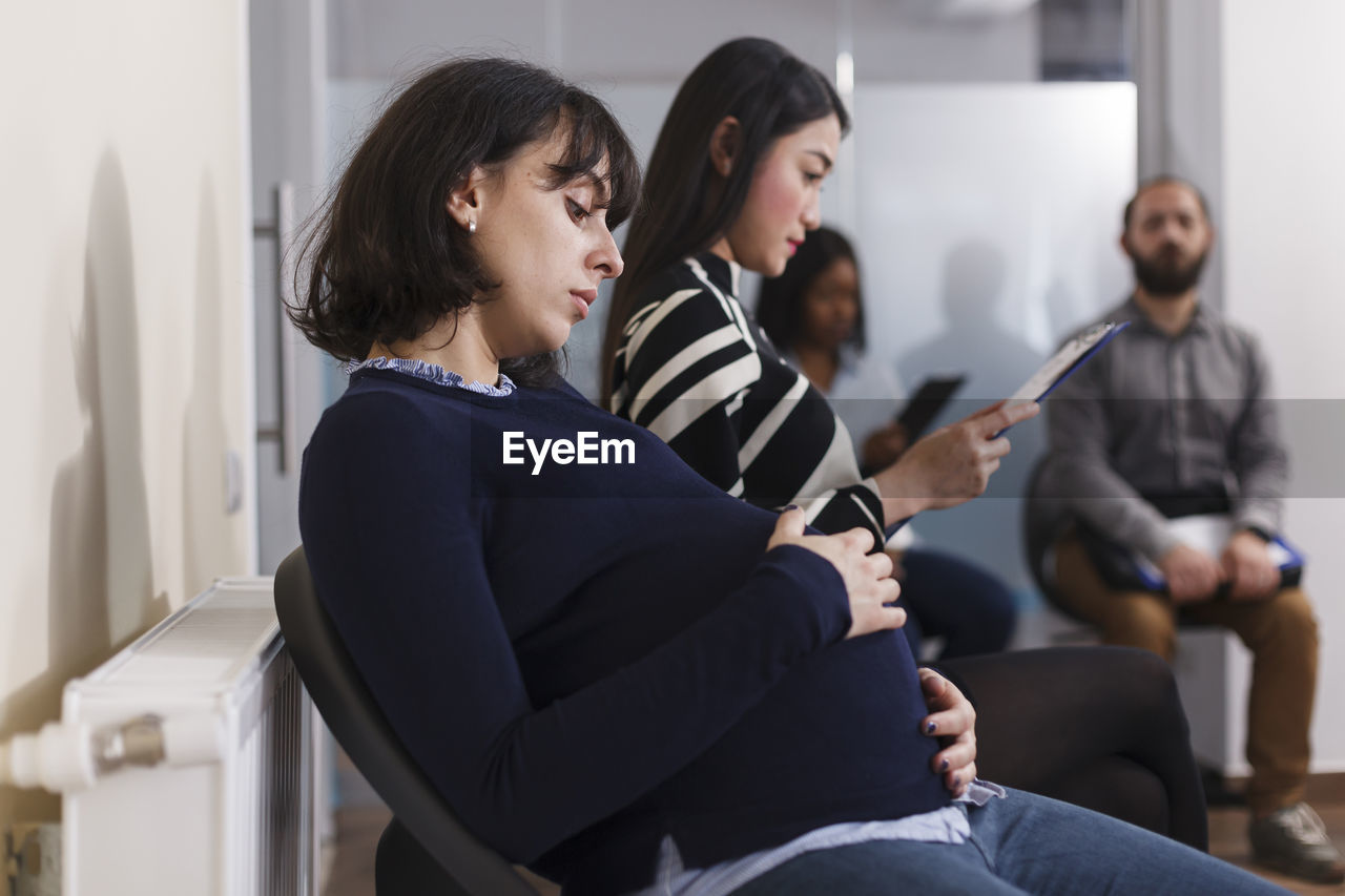 Side view of pregnant woman sitting at office