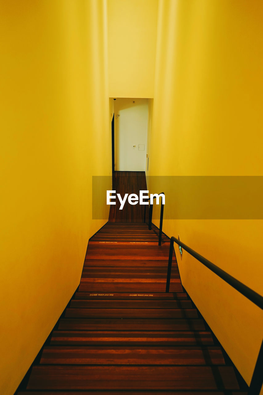 Empty corridor against yellow wall