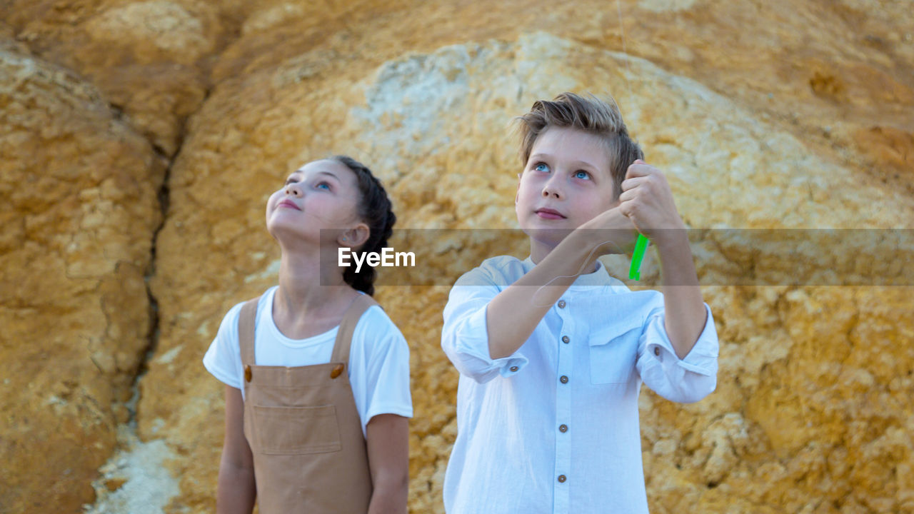 Surprised faces of children watching kite flying sky.