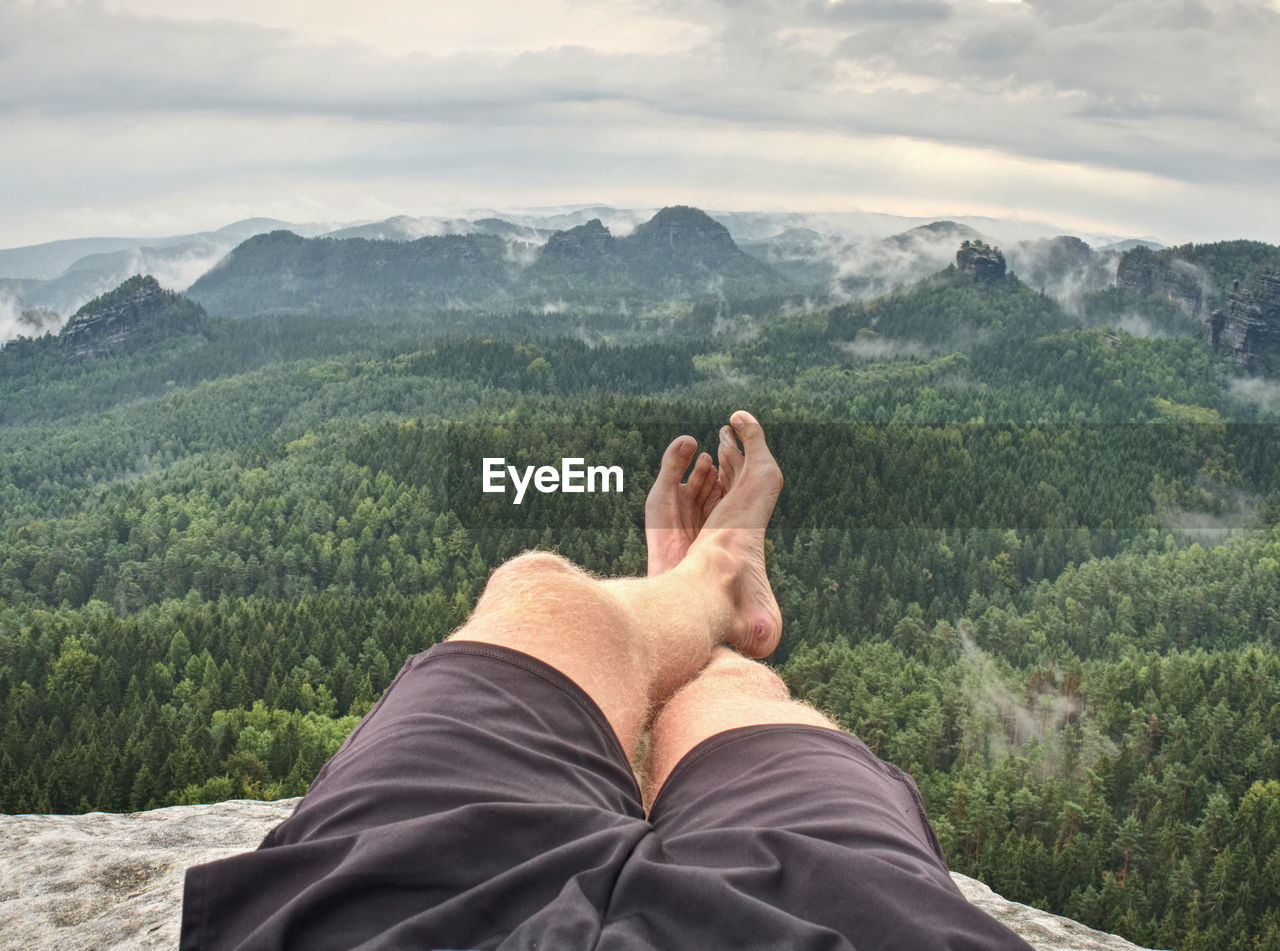 Man feet with hiking shoes on stone mountain background. spring morning in rocky mountains