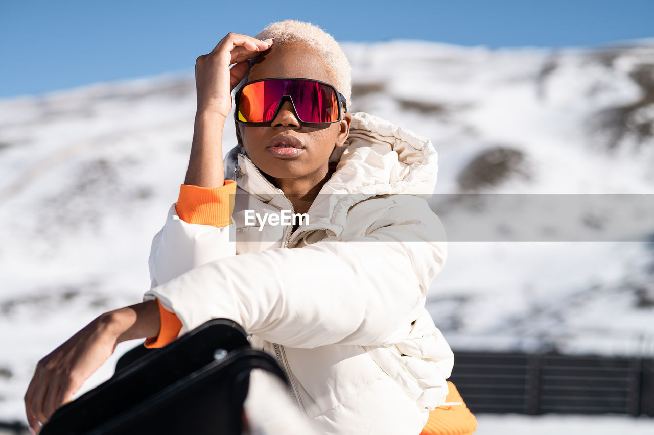 A young african american woman wearing sunglasses having fun in the snow on a winter day