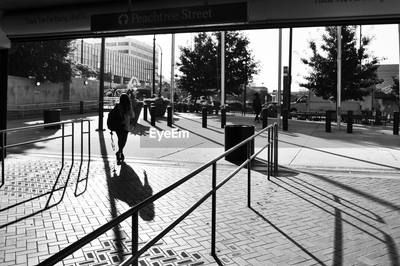 PEOPLE WALKING ON FOOTPATH BY STREET IN CITY