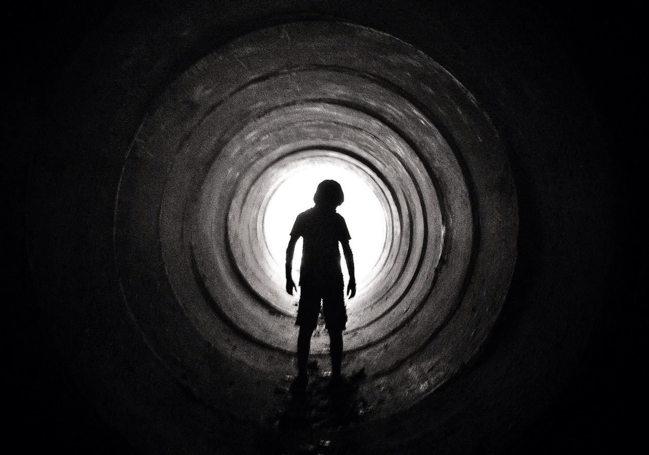 Silhouette boy standing in tunnel