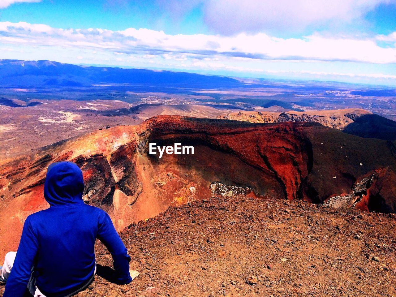 Rear view of man looking at mountains against sky