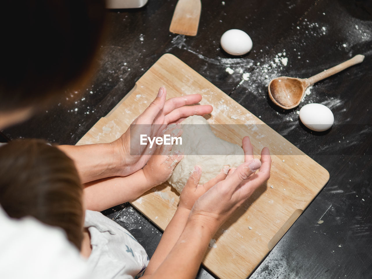 Mother and son are cooking together. mom and toddler knead dough from on black table. family time. 