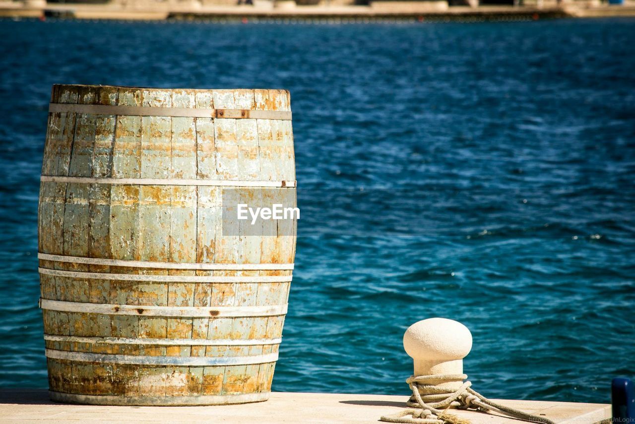 Close-up of rope at bollard against ripped blue water