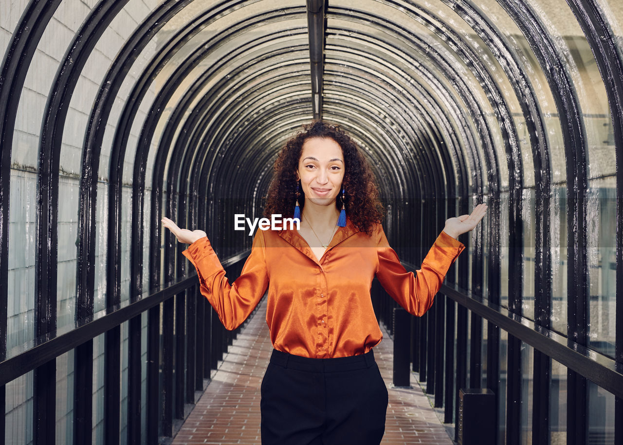 PORTRAIT OF YOUNG WOMAN STANDING AGAINST RAILING