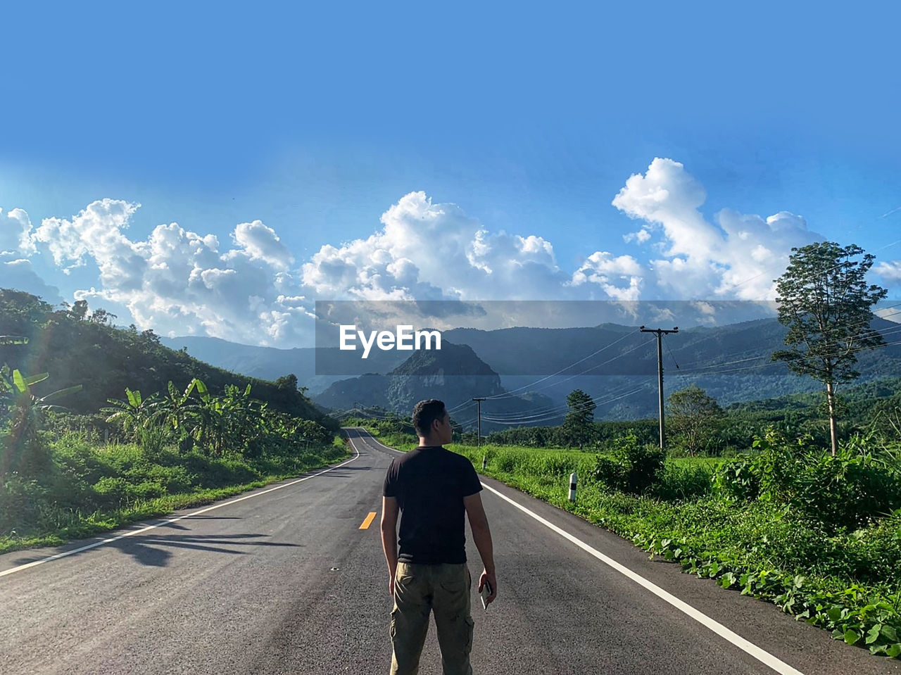 Rear view of man standing on road against sky