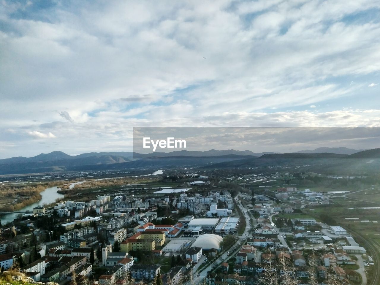 HIGH ANGLE VIEW OF CITYSCAPE AND MOUNTAINS AGAINST SKY