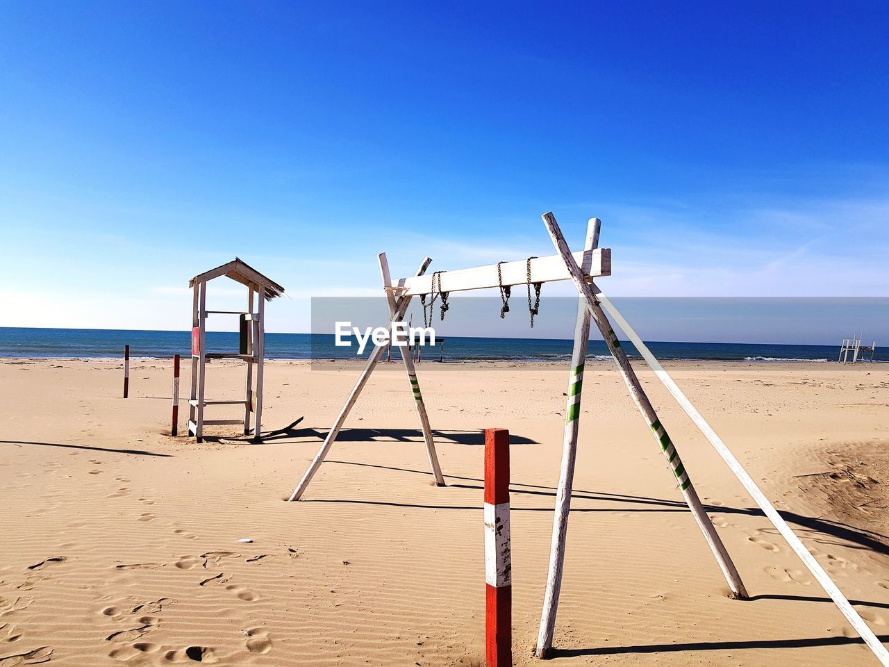 WOODEN POST ON BEACH AGAINST SKY