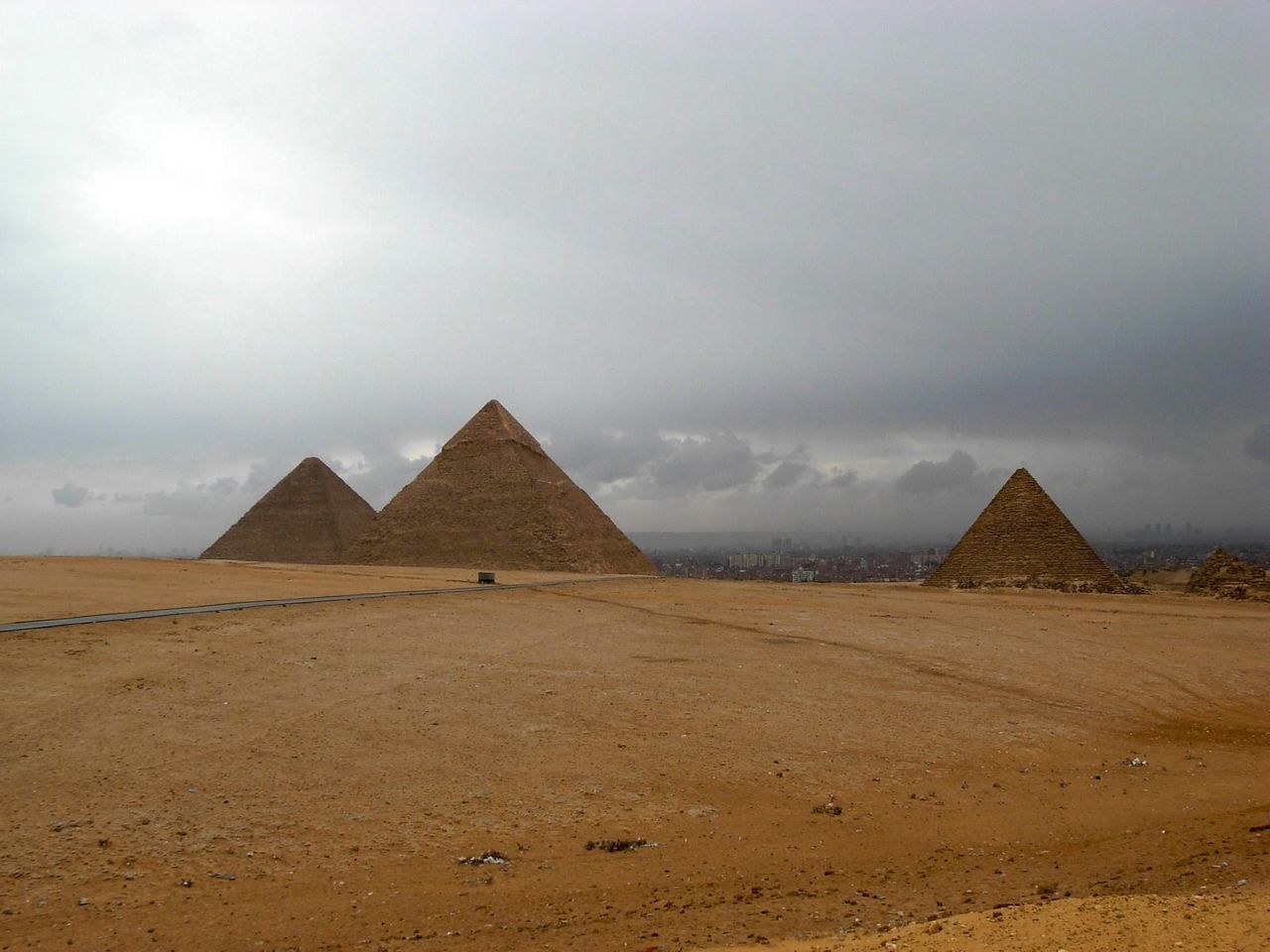 Pyramids in desert against cloudy sky