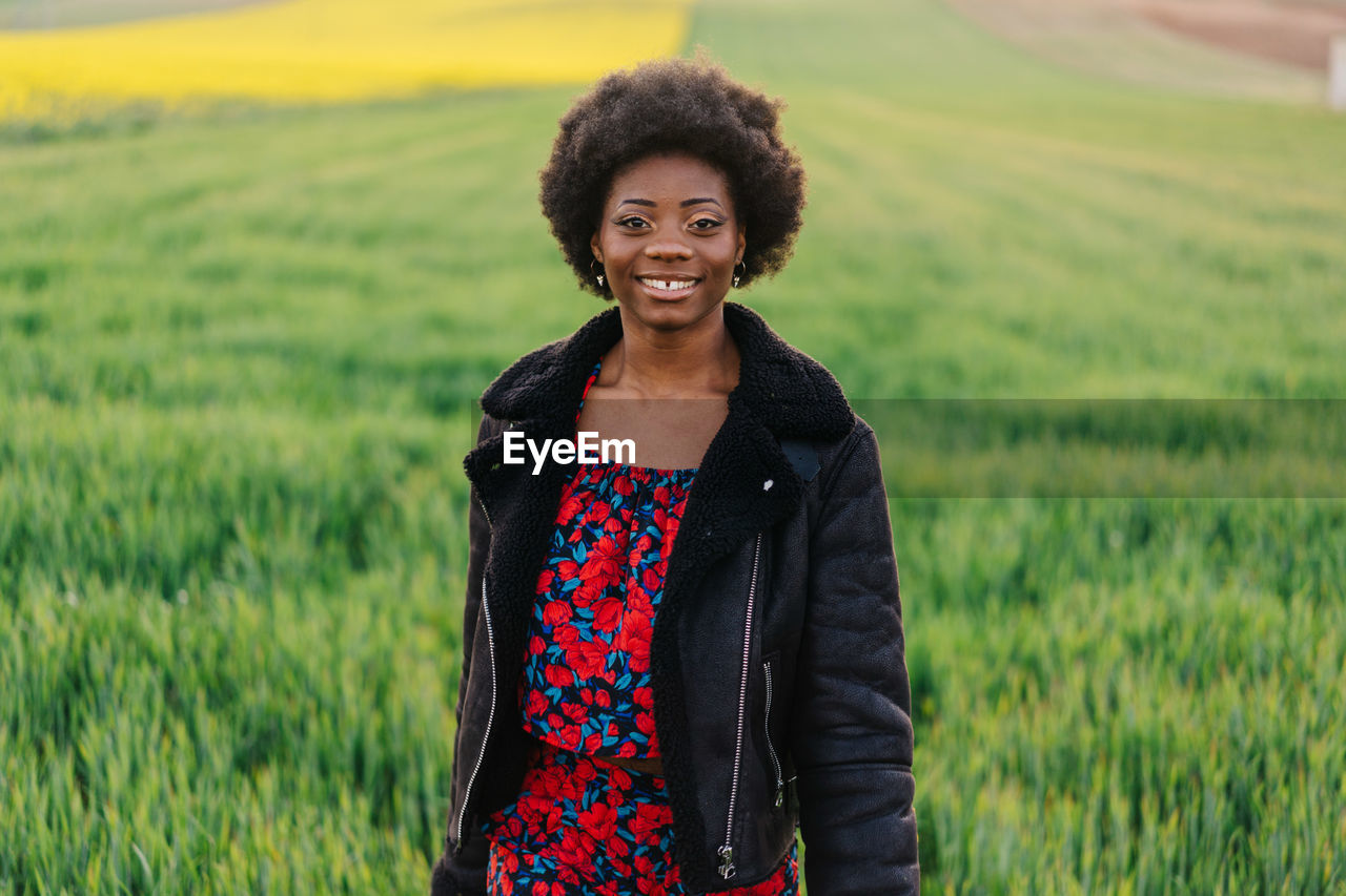 Portrait of smiling young woman standing on field