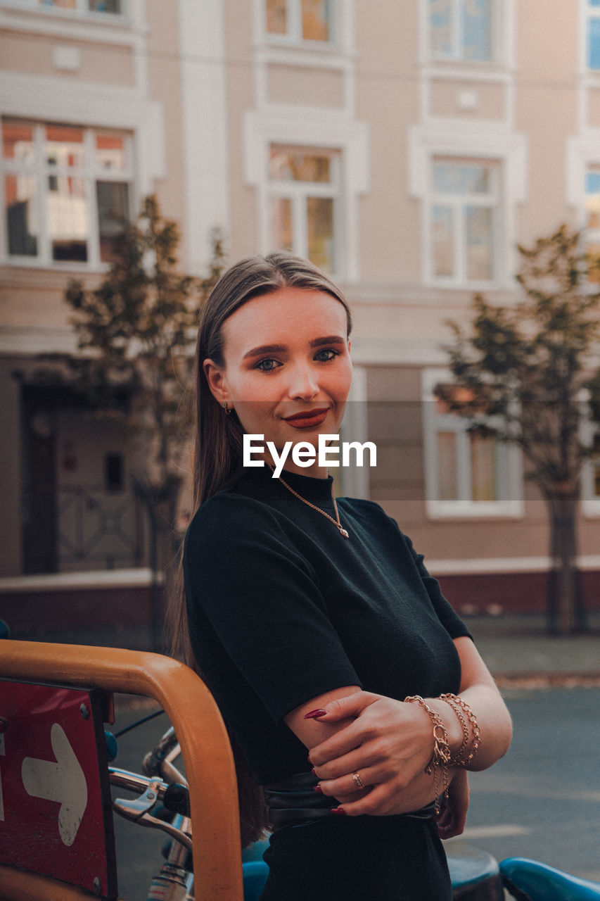 Portrait of smiling young woman standing against building