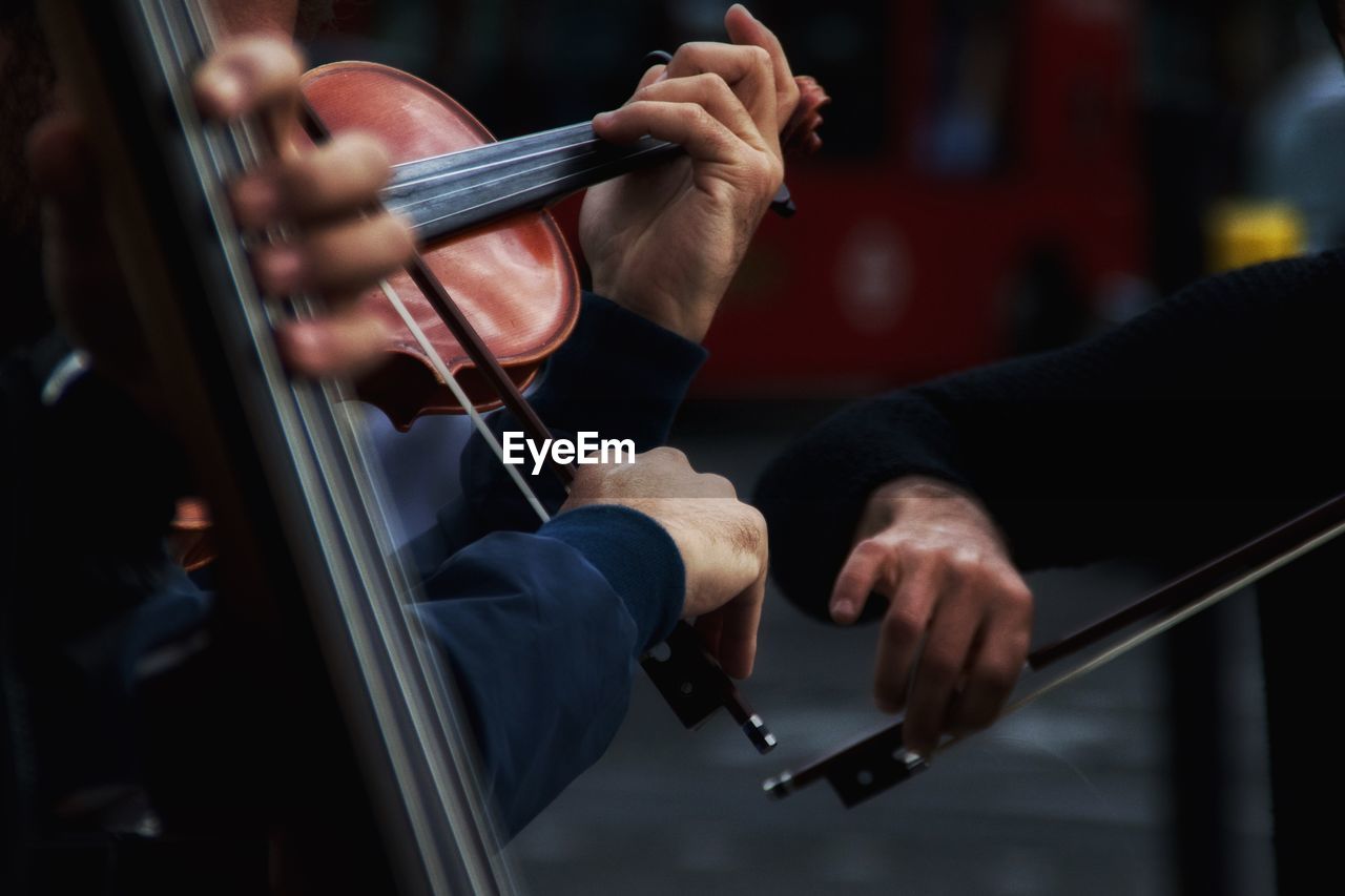 Cropped image of men playing violins on street